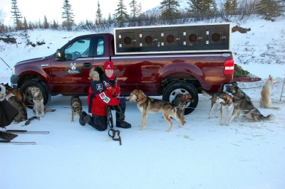 Aliy Zirkle poses for a quick picture with a few dogs from her "Red SP" team at the start.